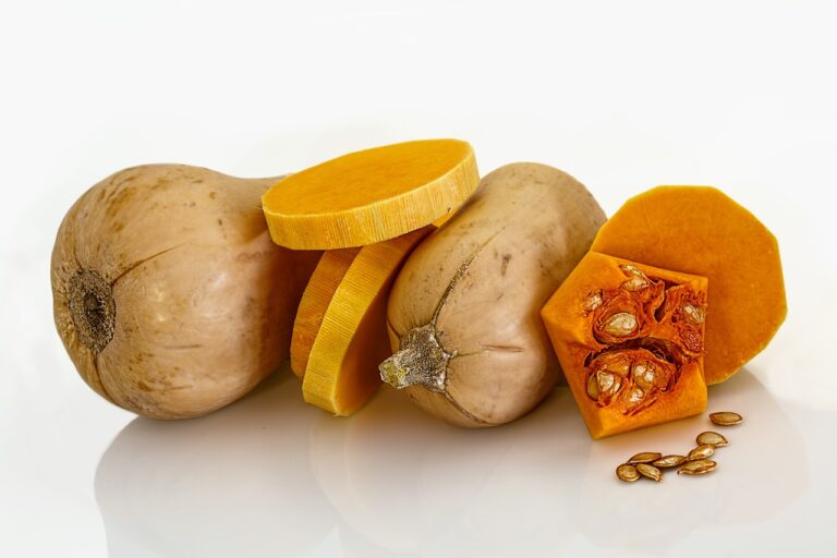 Whole butternut squash with sliced segments displaying the flesh and seeds against a white background.
